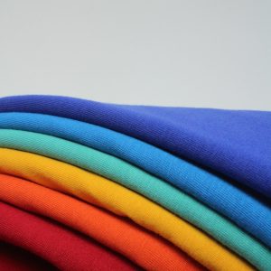 a stack of different colored t - shirts sitting on top of each other
